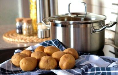 potatoes on a blue towel in front of a large pot